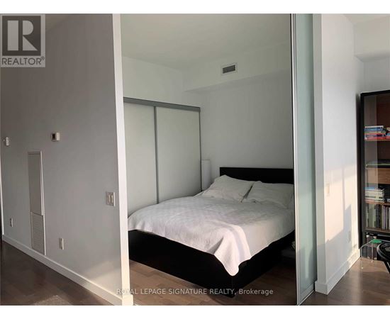 A bedroom with a bed, nightstand, and a cabinet.