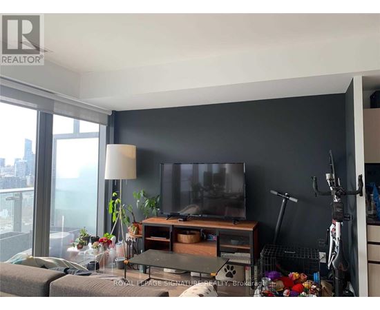 A living room with a grey couch and a television on a wooden stand.