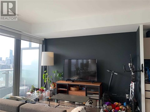 A living room with a grey couch and a television on a wooden stand.