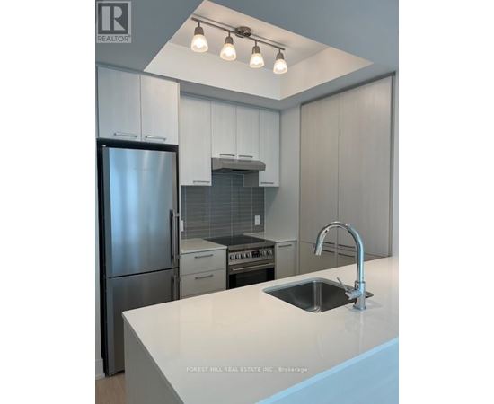 A kitchen with a stainless steel refrigerator and a sink with a faucet.