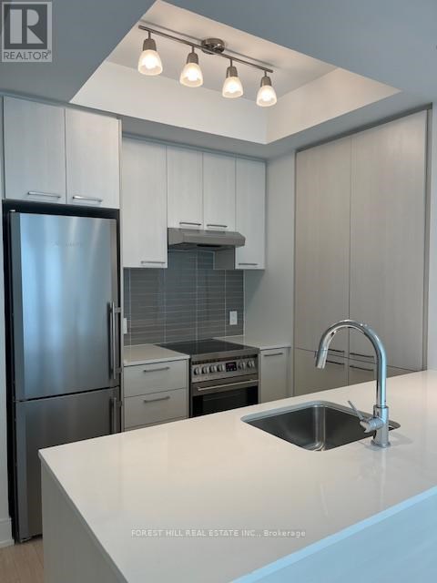 A kitchen with a stainless steel refrigerator and a sink with a faucet.