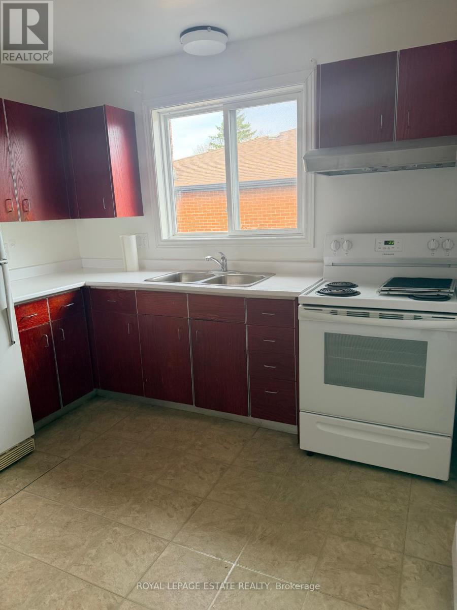 A kitchen with red cabinets and a white stove top oven.