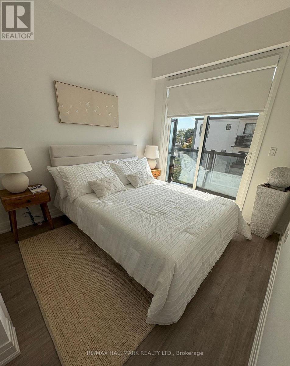 A bedroom with a large bed, a lamp, and a framed picture on the wall.