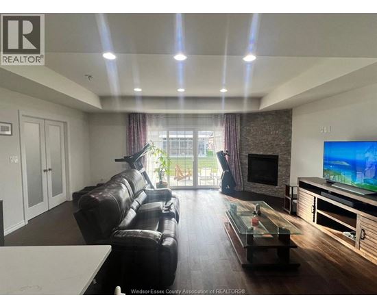 A living room with a black leather couch and a flat screen TV.