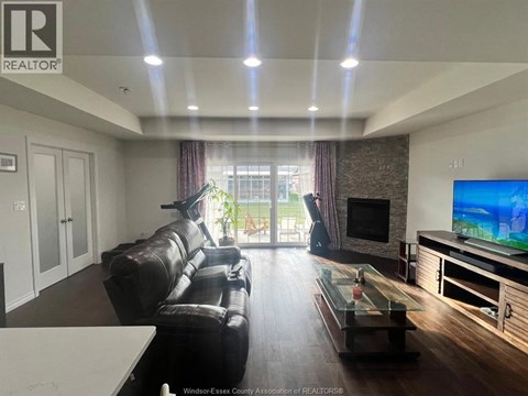 A living room with a black leather couch and a flat screen TV.