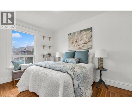 A bedroom with a large bed and a painting on the wall.