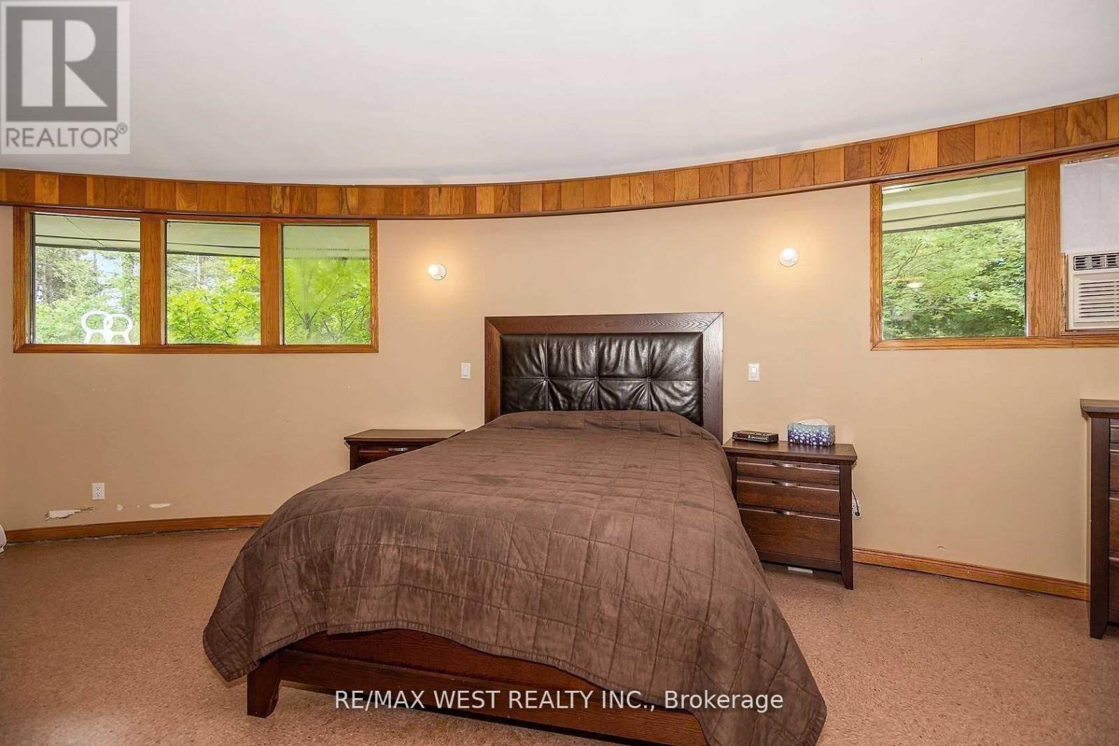 A bedroom with a large bed, a nightstand, and a window with a view of trees.