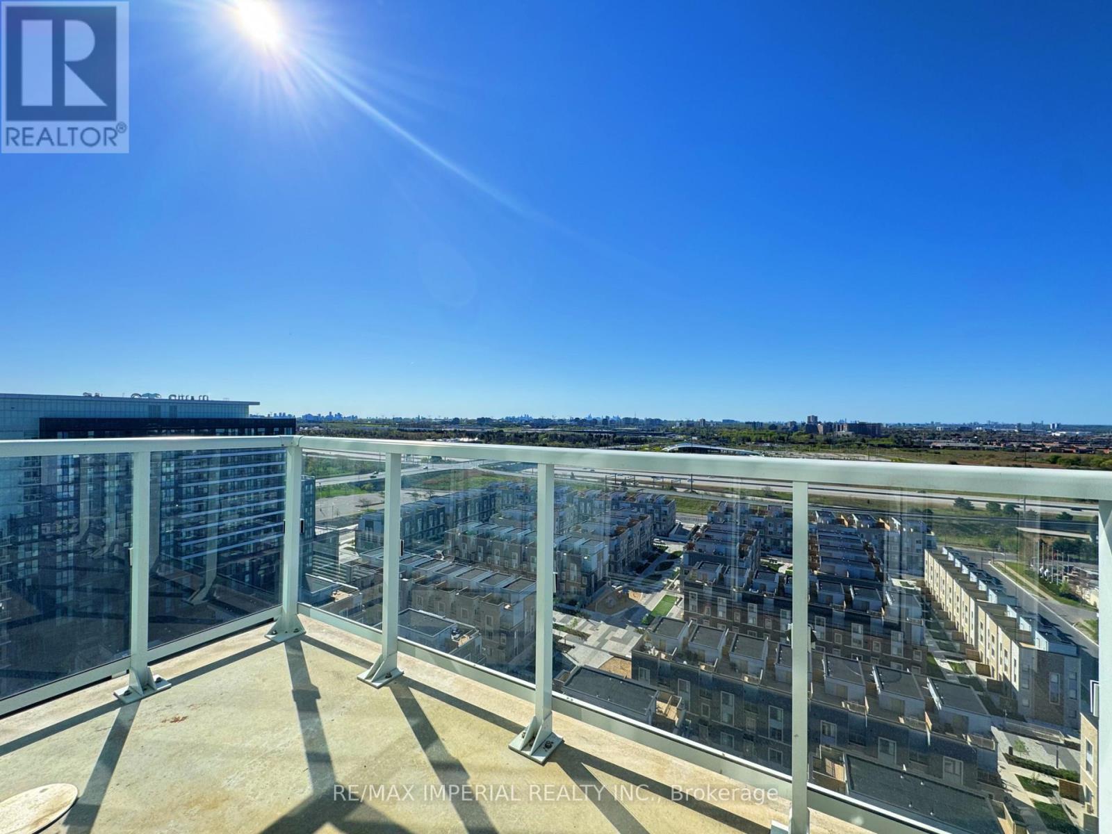 A balcony with a view of a cityscape and a bright sun in the sky.