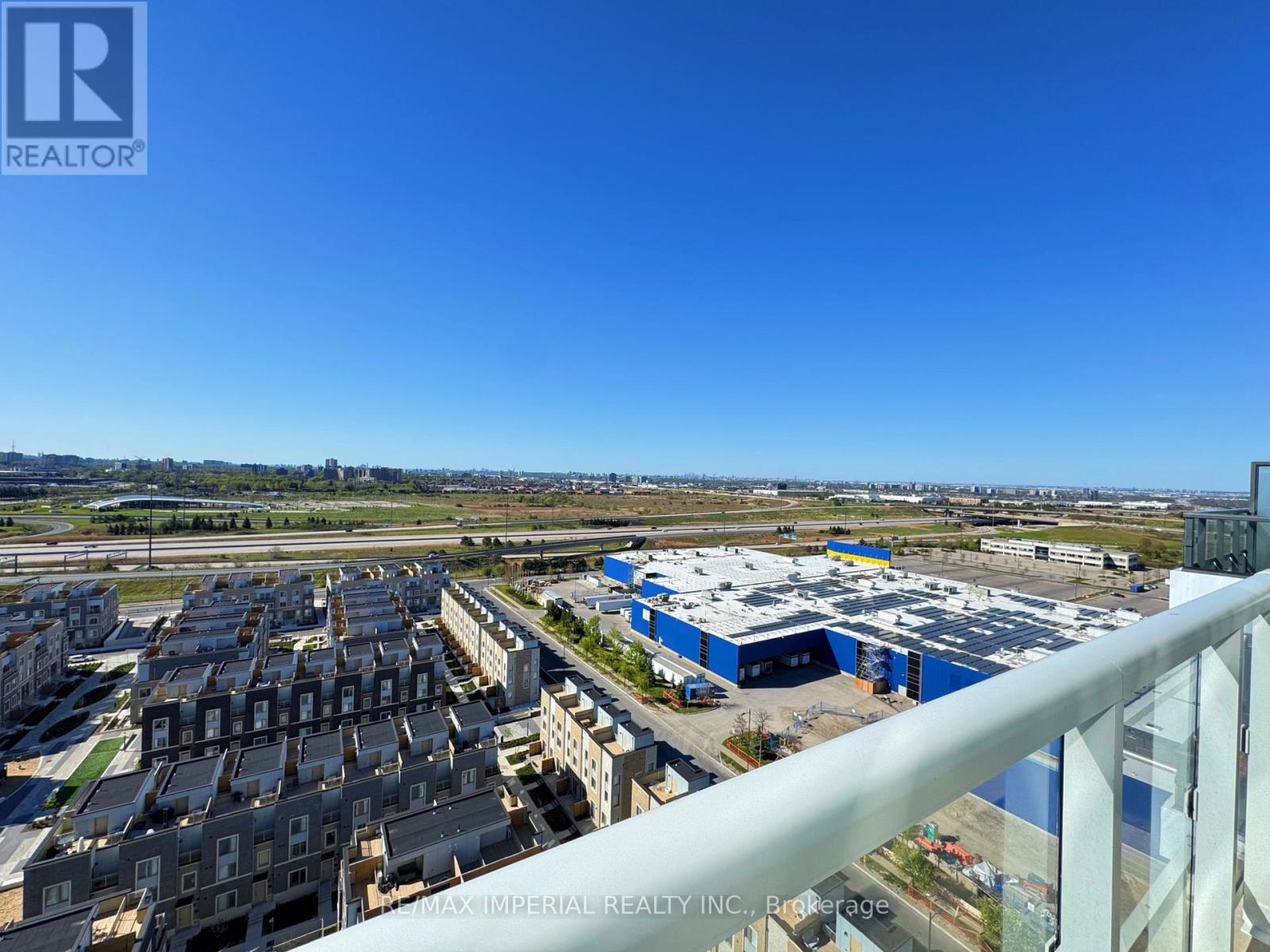 A view from a balcony overlooking a cityscape with buildings and a clear blue sky.