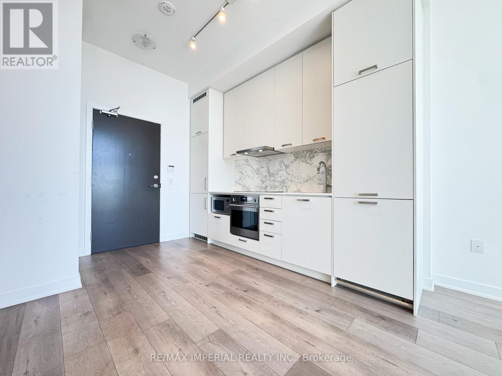 A kitchen with white cabinets and a black door.