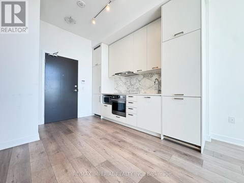 A kitchen with white cabinets and a black door.