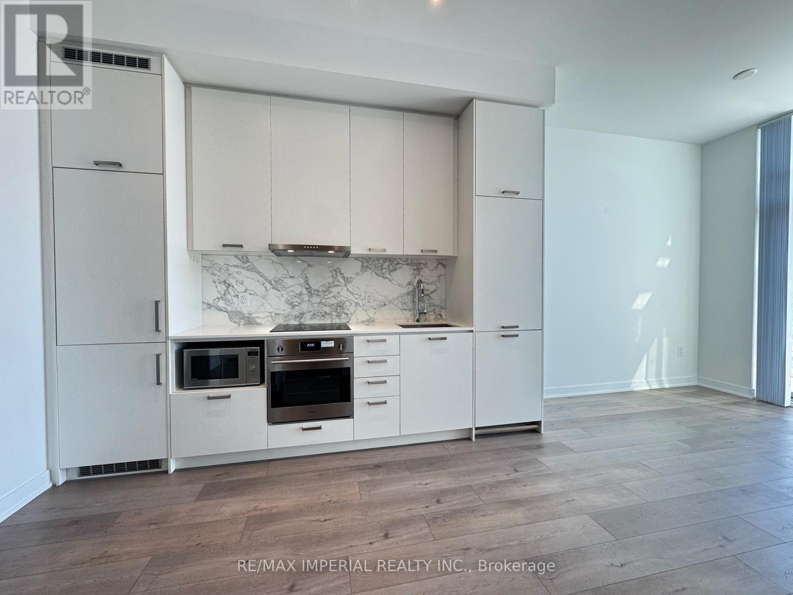 A kitchen with white cabinets and a marble backsplash.