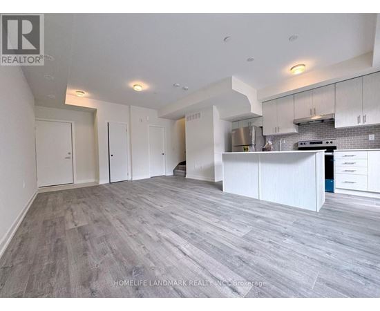 A spacious kitchen with white cabinets and a grey floor.