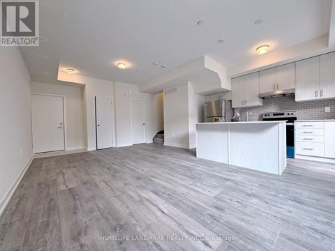 A spacious kitchen with white cabinets and a grey floor.