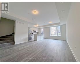 A spacious living room with wood flooring and a staircase on the left side.