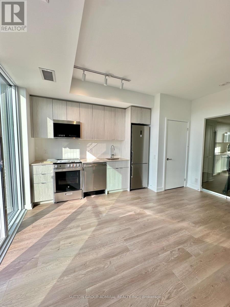 A modern kitchen with wooden flooring and stainless steel appliances.