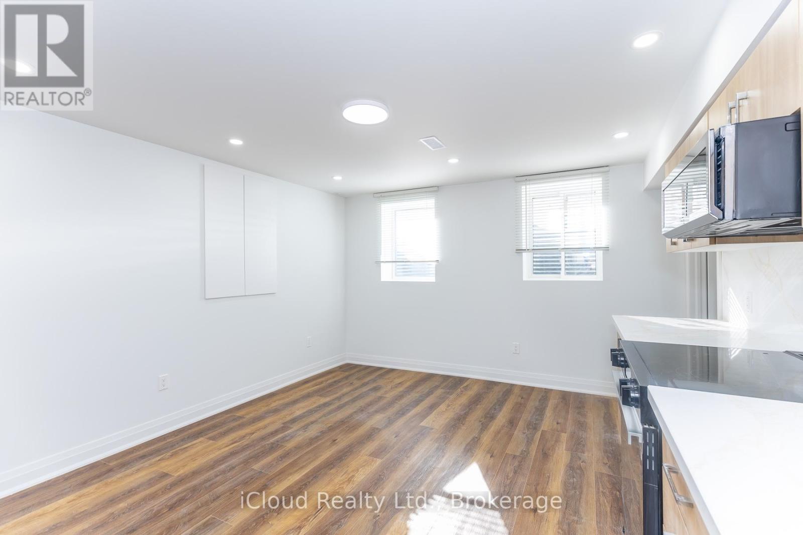 A spacious room with wooden flooring and white walls.