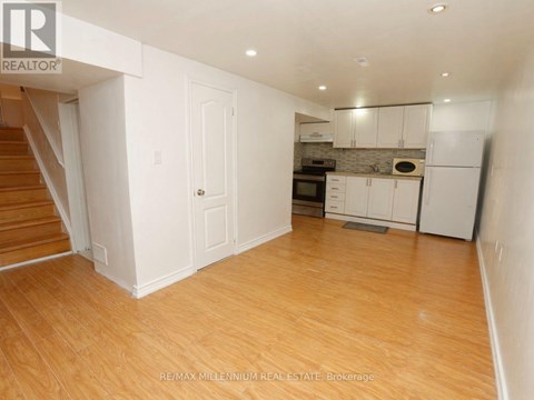 A room with wooden floors and white walls, with a staircase on the left side.