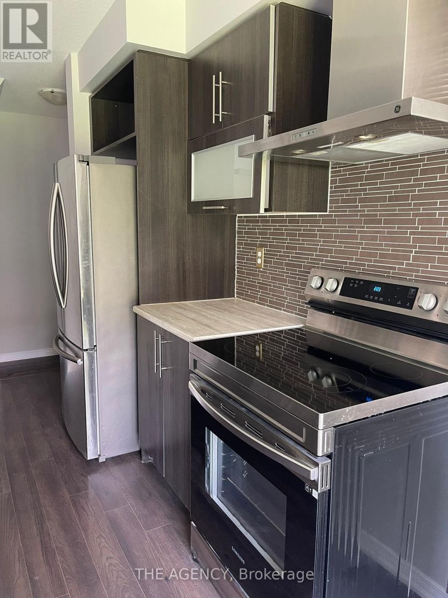 A modern kitchen with a refrigerator, oven, and stove top.