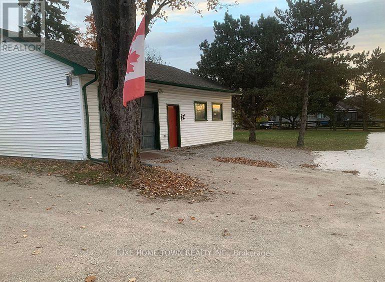 A small white building with a red door and a Canadian flag on a tree.
