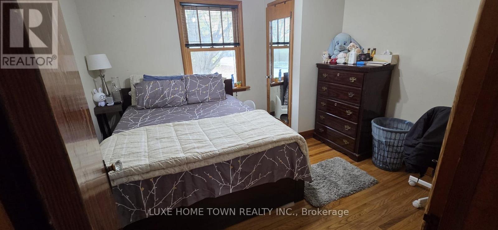 A bedroom with a bed, dresser, and window.