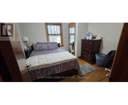 A bedroom with a bed, dresser, and window.