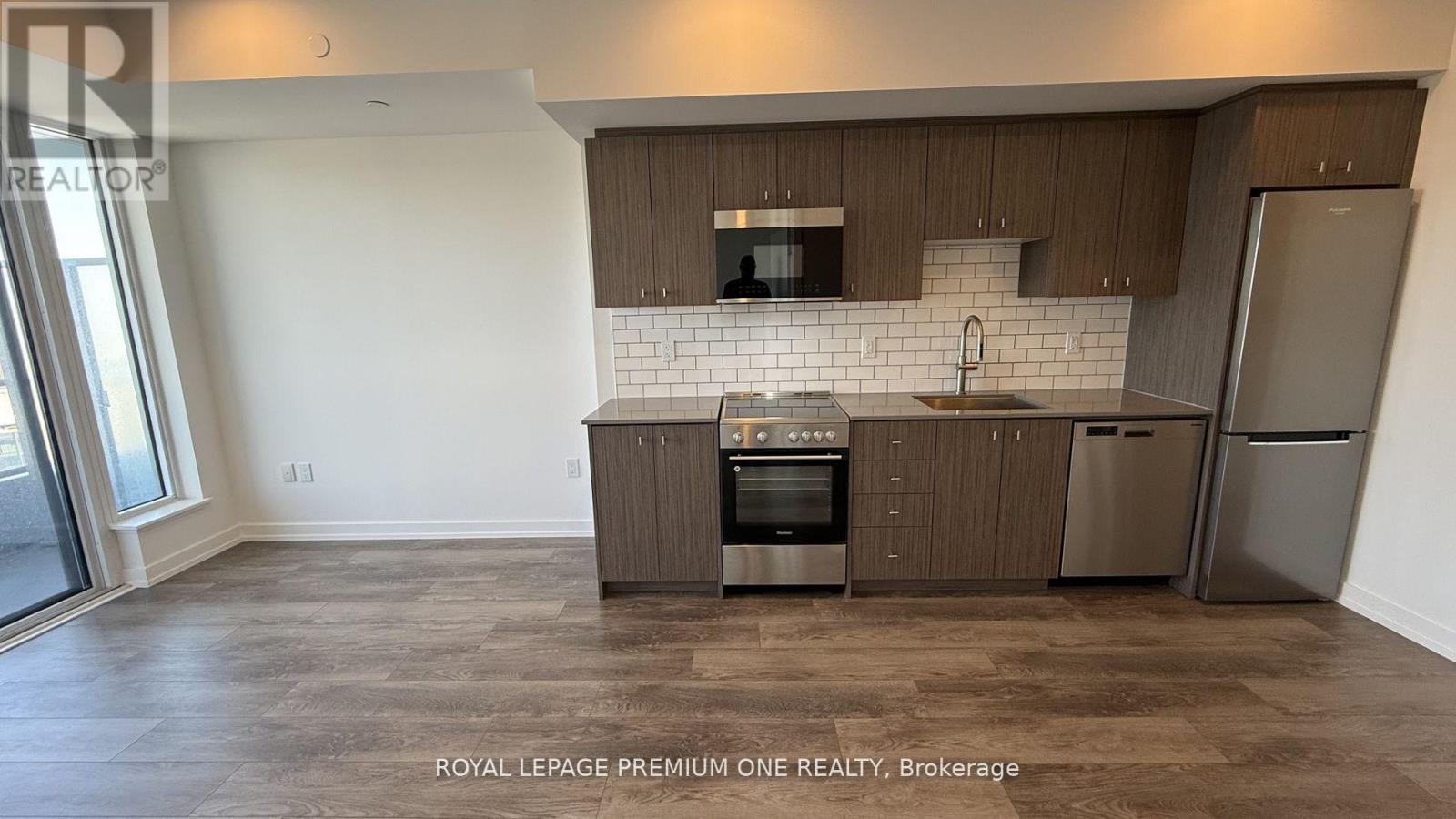 A kitchen with brown cabinets and a white backsplash.