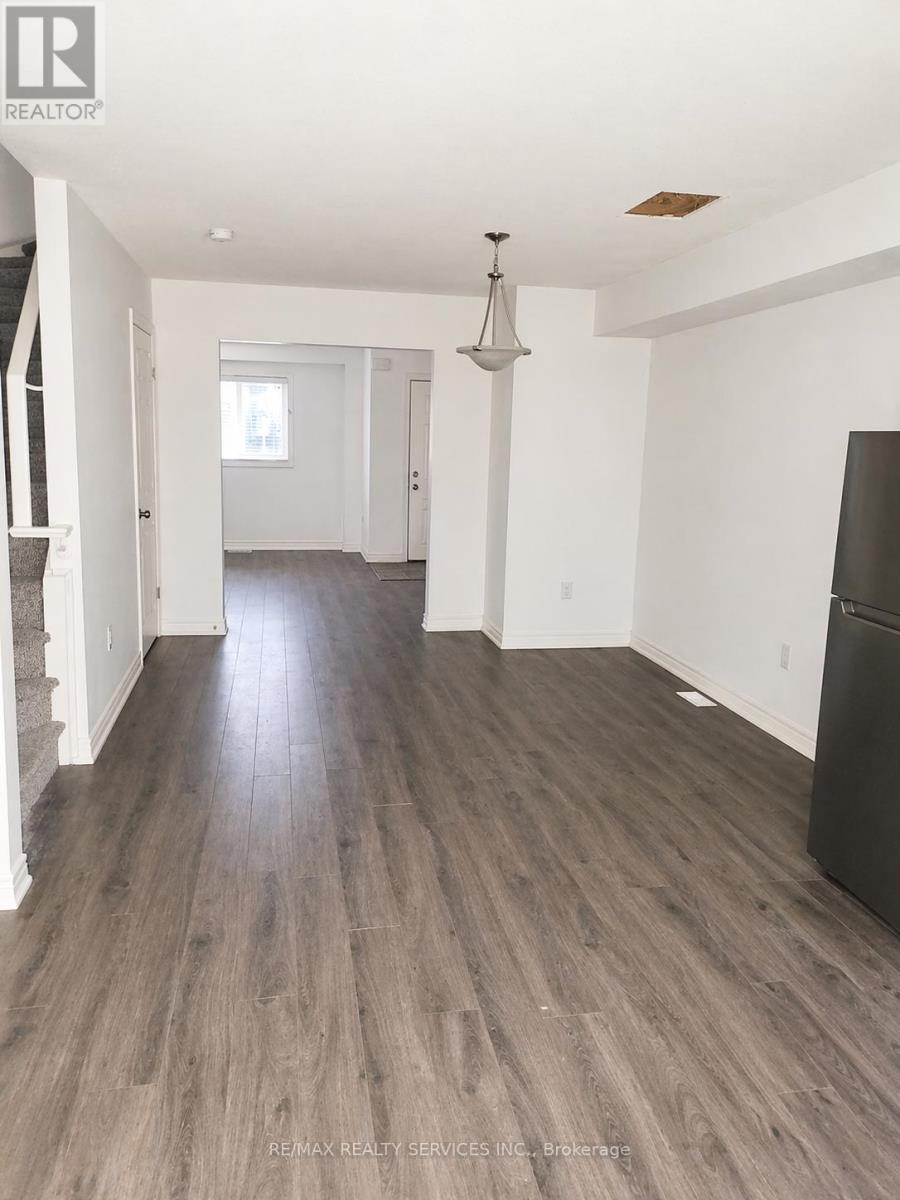 A spacious room with wooden flooring and a chandelier hanging from the ceiling.