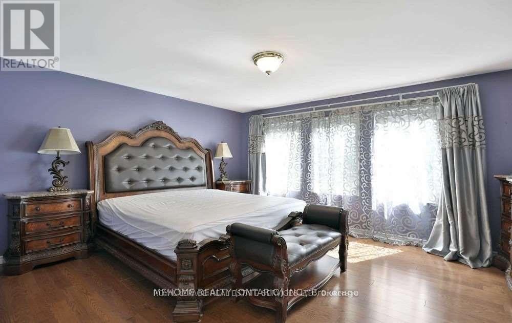A bedroom with a large bed, a bench, and a window with curtains.