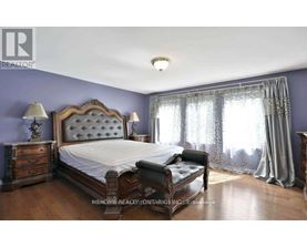 A bedroom with a large bed, a bench, and a window with curtains.