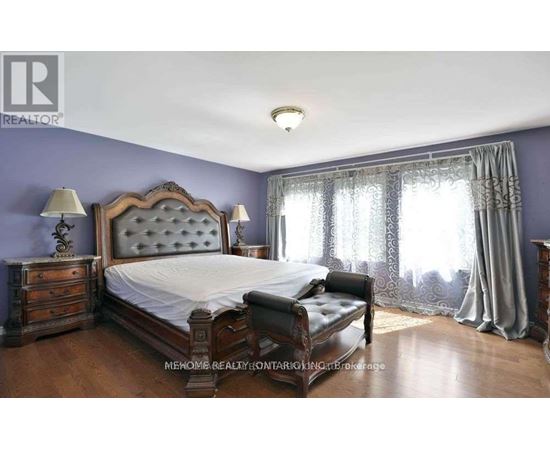 A bedroom with a large bed, a bench, and a window with curtains.