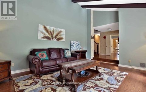 A brown leather couch sits in a living room with a rug on the floor.
