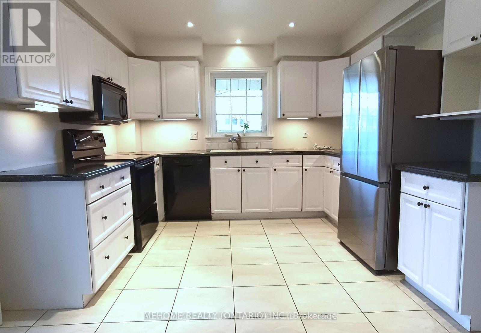 A kitchen with white cabinets and black appliances.