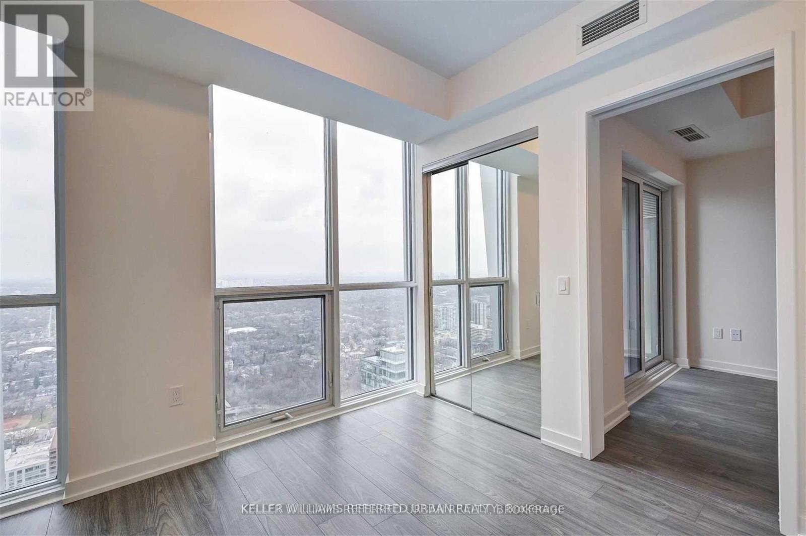 A spacious room with a view of the cityscape through large windows.