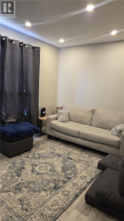 A living room with a grey couch, a blue ottoman, and a patterned rug.