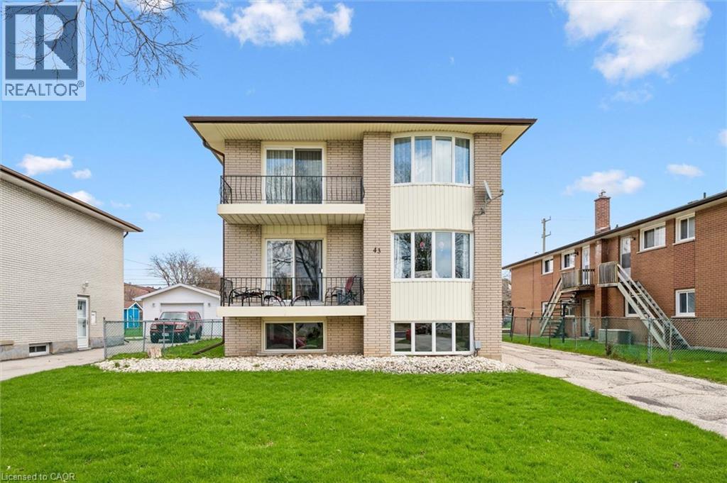 A modern two-story house with a balcony and a green lawn in front.