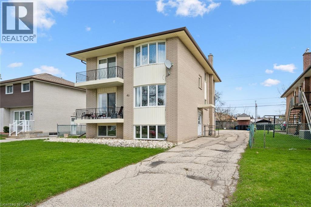 A two-story apartment building with a balcony and a driveway in front.