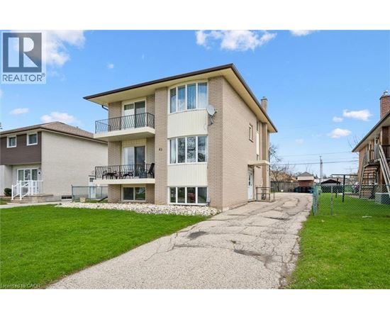 A two-story apartment building with a balcony and a driveway in front.