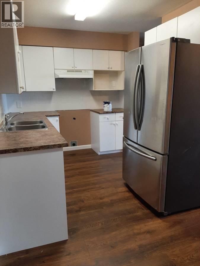 A kitchen with a refrigerator, sink, and cabinets.