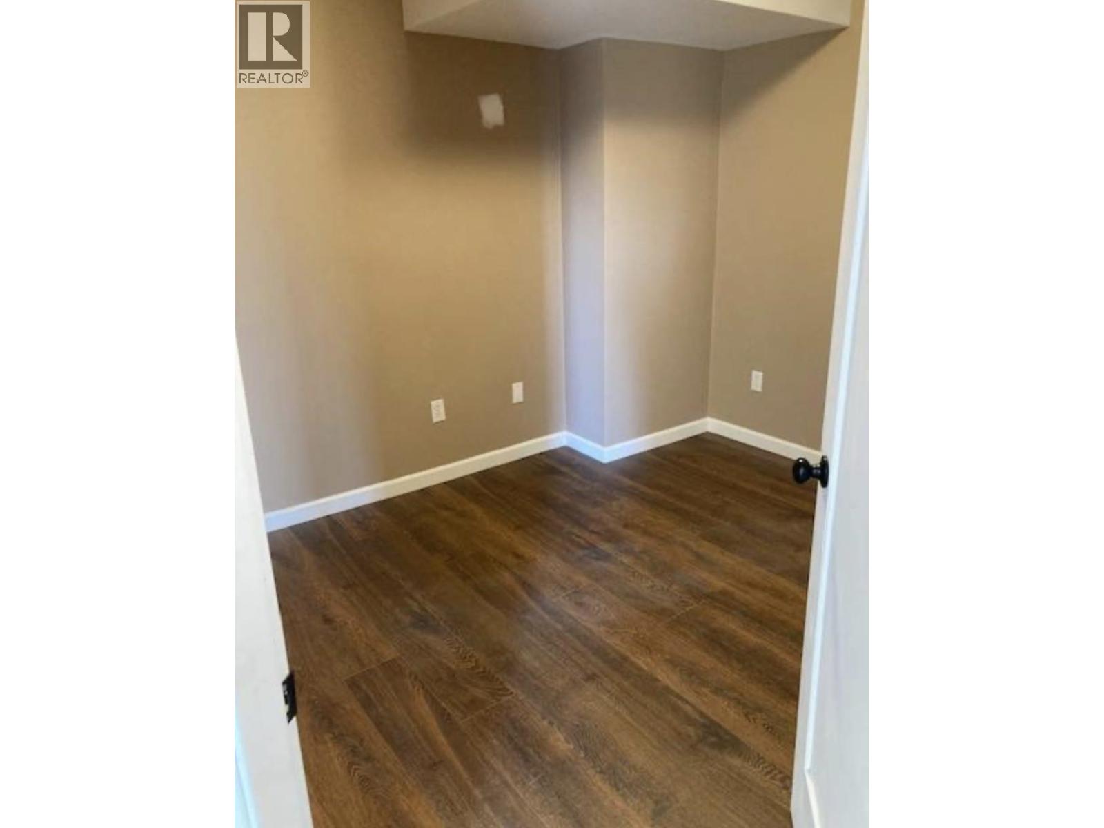 A room with wooden flooring and white walls.