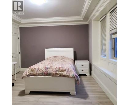 A bedroom with a bed, nightstand, and a window with blinds.