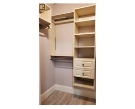 A white shelving unit with a drawer is mounted on a wall.