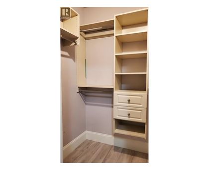 A white shelving unit with a drawer is mounted on a wall.