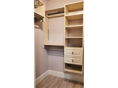 A white shelving unit with a drawer is mounted on a wall.