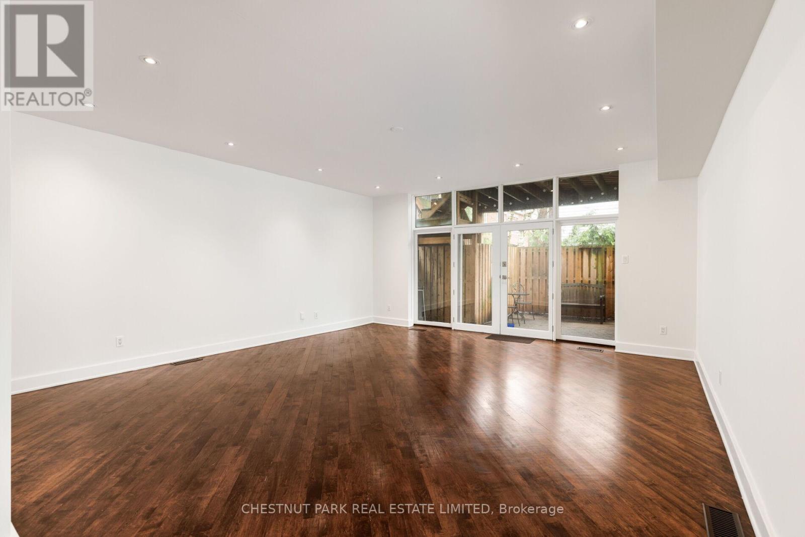 A spacious room with wooden flooring and white walls.