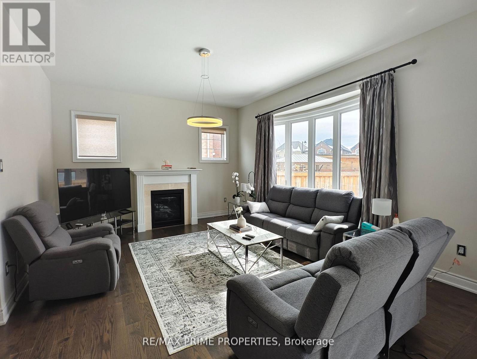 A living room with a grey couch, a grey chair, a grey coffee table, a fireplace, and a television.
