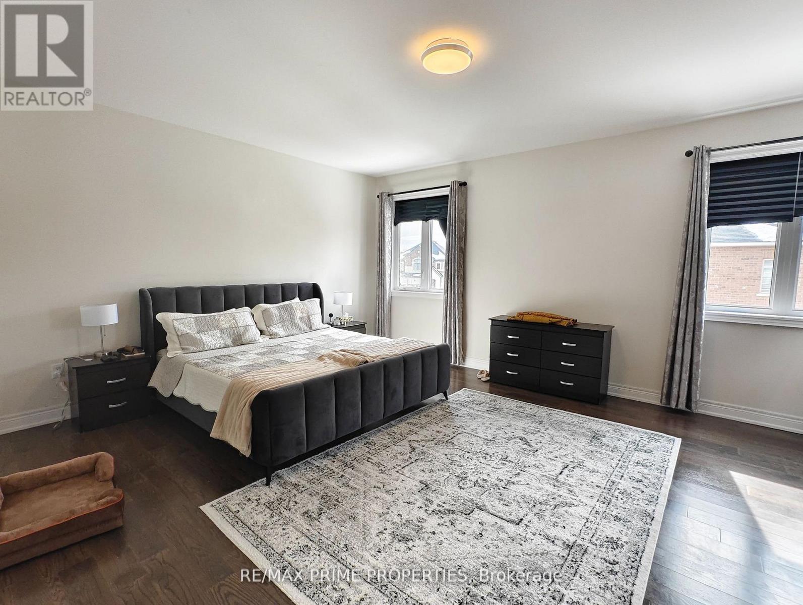A bedroom with a large bed, a dresser, and a window with blinds.
