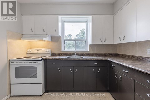 A white oven and sink in a kitchen with a window.