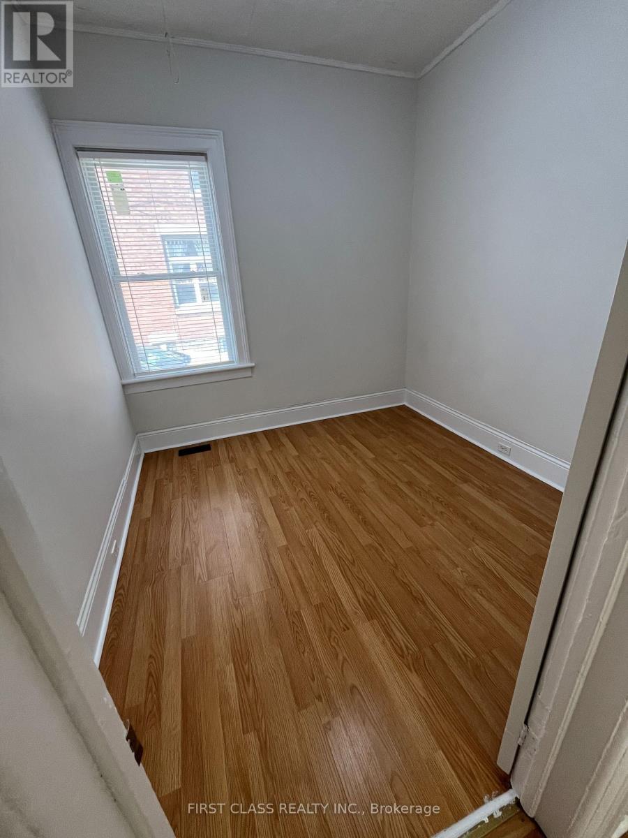 A room with wooden flooring and a window showing a building outside.