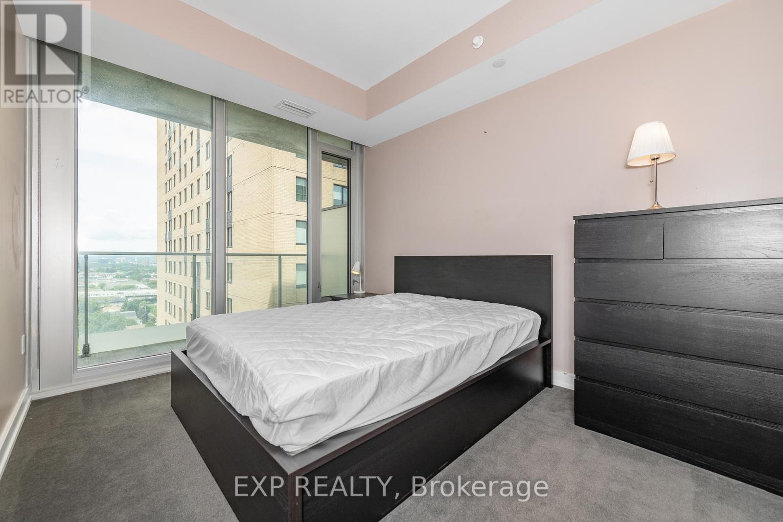 A bedroom with a large bed and a window overlooking a cityscape.